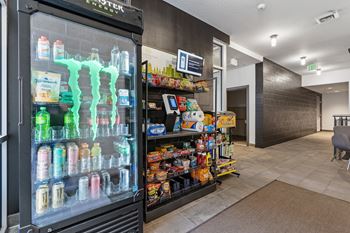 A monster energy drink machine is in the foreground of a convenience store.